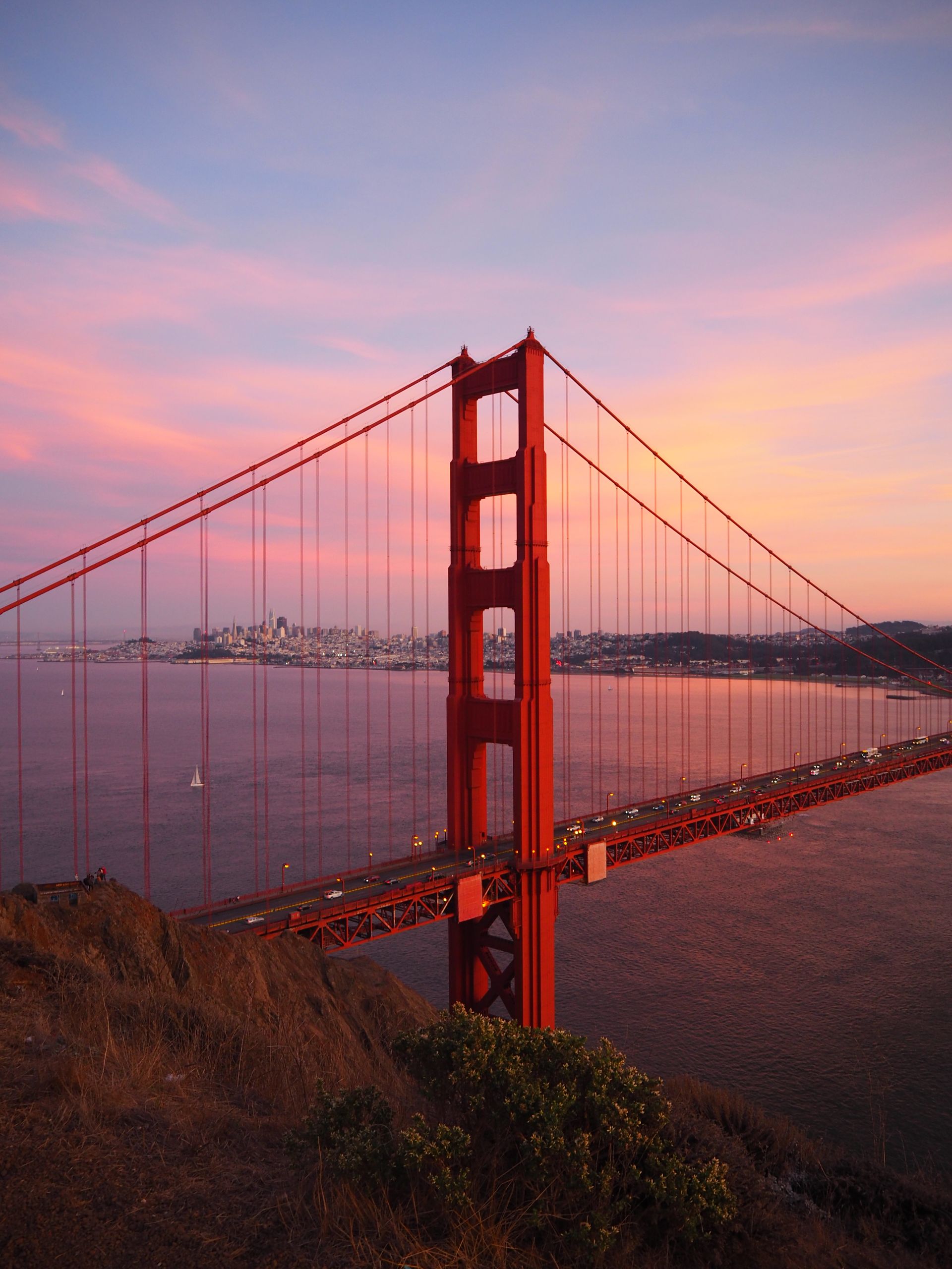 Captivating sunset view of the iconic Golden Gate Bridge with pink skies over San Francisco Bay.