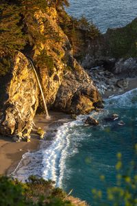 Experience the serene beauty of McWay Falls cascading into the ocean at sunset in Big Sur, California.